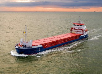 A real photograph of a coastal cargo vessel underway at sea
