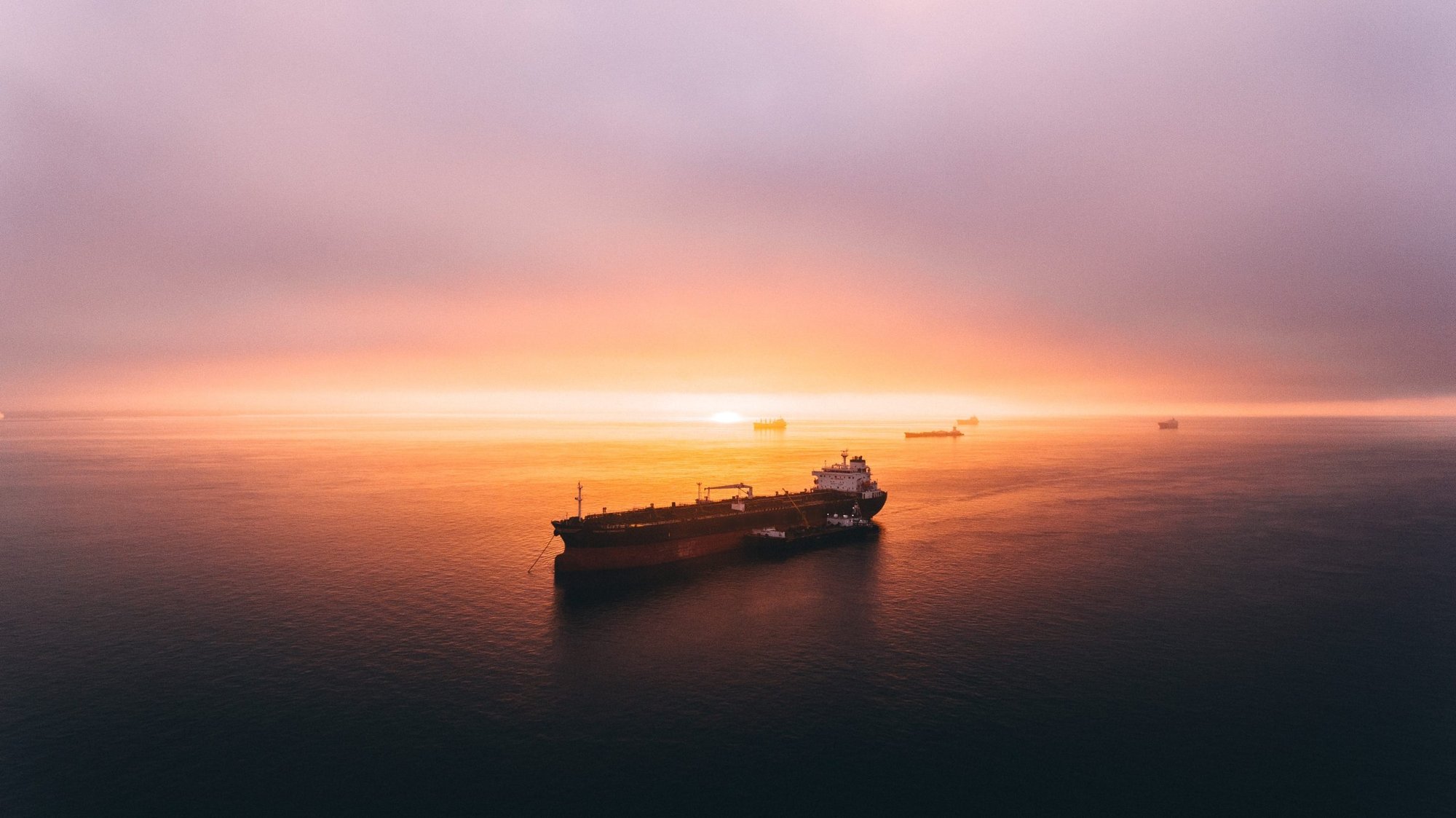 A VLCC silhouetted against a sunset at sea